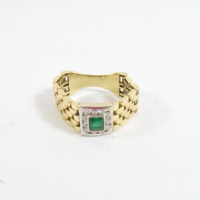 gros plan d'une bague en or avec une pierre verte