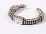 an old silver bracelet with a tag on it on a white surface