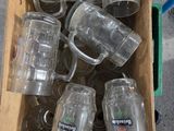 a box full of empty beer mugs sitting on the ground