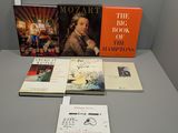 plusieurs livres posés sur une table dans une pièce où est accrochée une horloge au mur