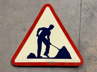 un panneau triangulaire sur lequel figure l'image d'un homme en train de pelleter de la terre