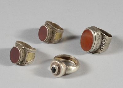 four rings with red stones on them sitting on top of a white surface