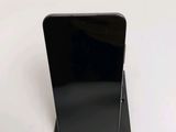 the back of a black cell phone sitting on top of a white table