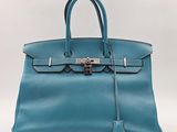 un sac à main en cuir bleu muni d'un cadenas sur la poignée