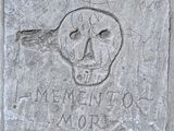 bloc de béton sur lequel sont gravés un crâne et des mots