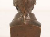 an antique bronze bust of a woman on a wooden base