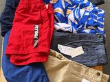Plusieurs paires de pantalons pour hommes sont disposées sur une caisse en bois