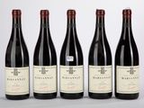 quatre bouteilles de vin rouge sont alignées sur une table