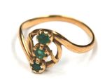 an image of a close up of a gold ring with green stones