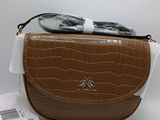 un sac à main marron et blanc, sur lequel sont posées des lunettes de soleil, posé sur une surface blanche