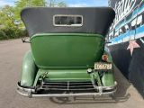an old green car parked in front of a building