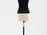 un haut noir posé sur un pied de mannequin, devant un fond blanc