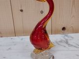 un oiseau en verre rouge posé sur une table en marbre
