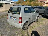 une petite voiture garée sur un parking, à côté d'autres voitures