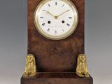 une image représentant une horloge en bois flanquée de deux lions de chaque côté
