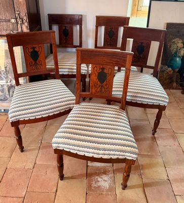 quatre chaises en bois, dont les assises sont recouvertes d'un tissu rayé, sont posées sur un sol carrelé