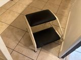 a black and white step stool sitting on a tiled floor