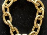 a close up of a gold chain bracelet on a black surface