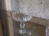 three glasses on a glass shelf with a blue and white vase