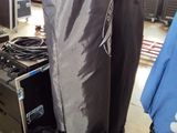 un grand sac noir posé par terre à côté d'une enceinte