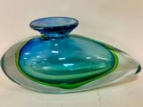 a blue and green glass vase on a white table