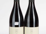 deux bouteilles de vin rouge posées l'une à côté de l'autre sur une surface blanche