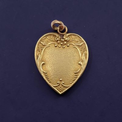 un gros plan d'un pendentif en forme de cœur doré sur fond bleu