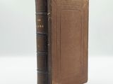 an old book with a brown cover sitting on top of a white surface