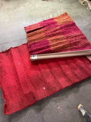 a red rug on the floor next to a roll of carpet
