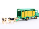 a green toy truck with two cows in front of it