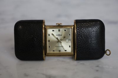 a black watch with a gold case on a marble surface