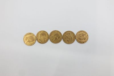 un groupe de cinq pièces d'or posées sur une surface blanche