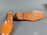 pair of men ' s tan leather shoes sitting on a gray surface