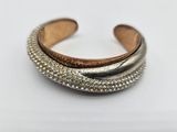 a close up of a silver and gold cuff bracelet on a white surface