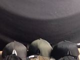 several hats are sitting on a wooden table with a black backdrop in the background