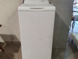 une machine à laver blanche posée dans une pièce, à côté d'une chaise