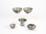 four bowls and a bowl on a stand on a white surface