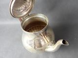 a silver tea pot with a lid on a table