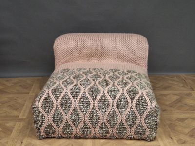 a pink and grey chair sitting on a wooden floor