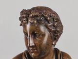 an antique bronze statue of a woman sitting on a stool