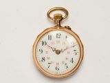 une montre de poche en or avec un cadran blanc sur une surface blanche