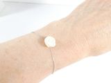 Quelqu'un porte un bracelet sur lequel est fixé un bouton blanc.