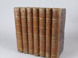 five old books sitting on top of each other on a white surface