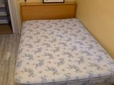un lit qui se trouve dans une petite chambre avec un tableau accroché au mur