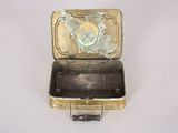 a small metal box with a metal lid on a white surface