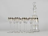 six wine glasses and a decanter on the table
