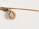 an image of a gold broochle with a tear shaped broochle on it