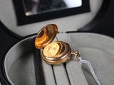a gold pocket watch sitting in a case on a table