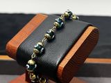 vitrine en bois sur laquelle est exposé un bracelet en perles noires et dorées