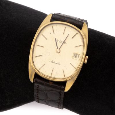 une photo d'une montre en or posée sur un tissu noir